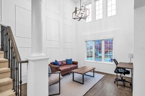 A spacious room with a staircase, a brown leather sofa with blue cushions, a wooden coffee table, and a desk with a chair. - Minutes to Thermëa Spa, Hwy 401, GO Train & Golf (Ajax)