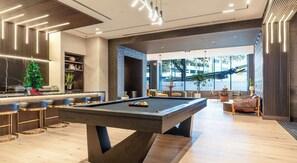 A pool table in a modern lounge area with bar seating and a view of the outside. - Luxury 1BD | Downtown Dallas | Pool+Gym (Dallas)