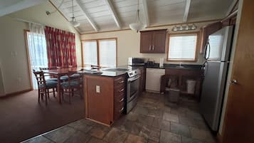 A kitchen with a central island, wooden cabinets, a refrigerator, and a microwave.