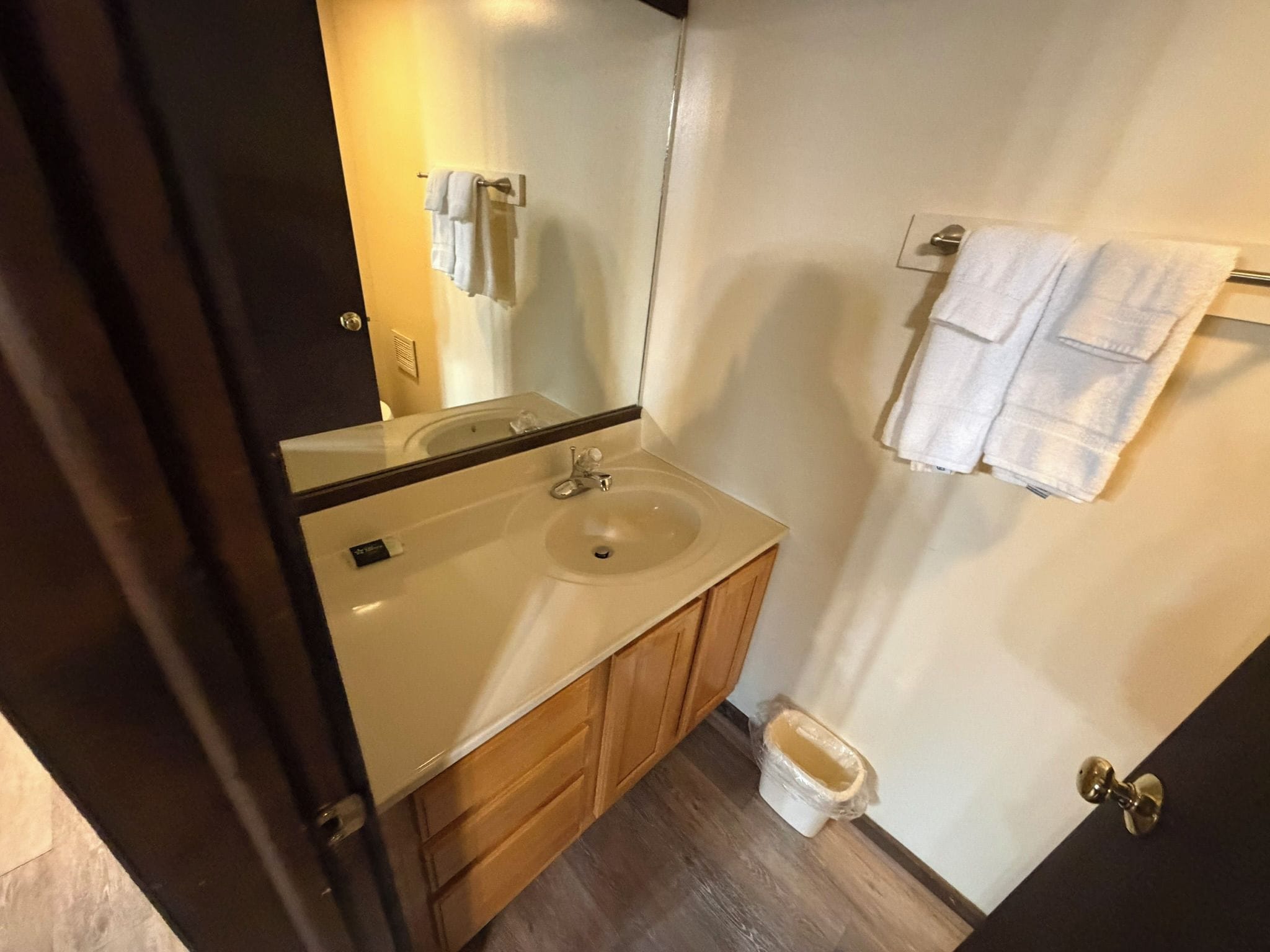 A bathroom with a sink, mirror, wooden cabinets, and a toilet.