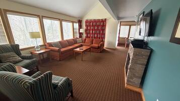 A living room with a sectional sofa, a striped armchair, a coffee table, and a stone fireplace.