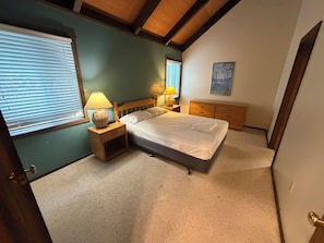 A bedroom with a bed, bedside lamps, a nightstand, a dresser, and a window with blinds. - The Pedestals by CoolVacay (Basye)