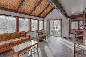 Un salón amplio con techos altos, ventanas grandes, un sofá, una silla y una zona de comedor.
