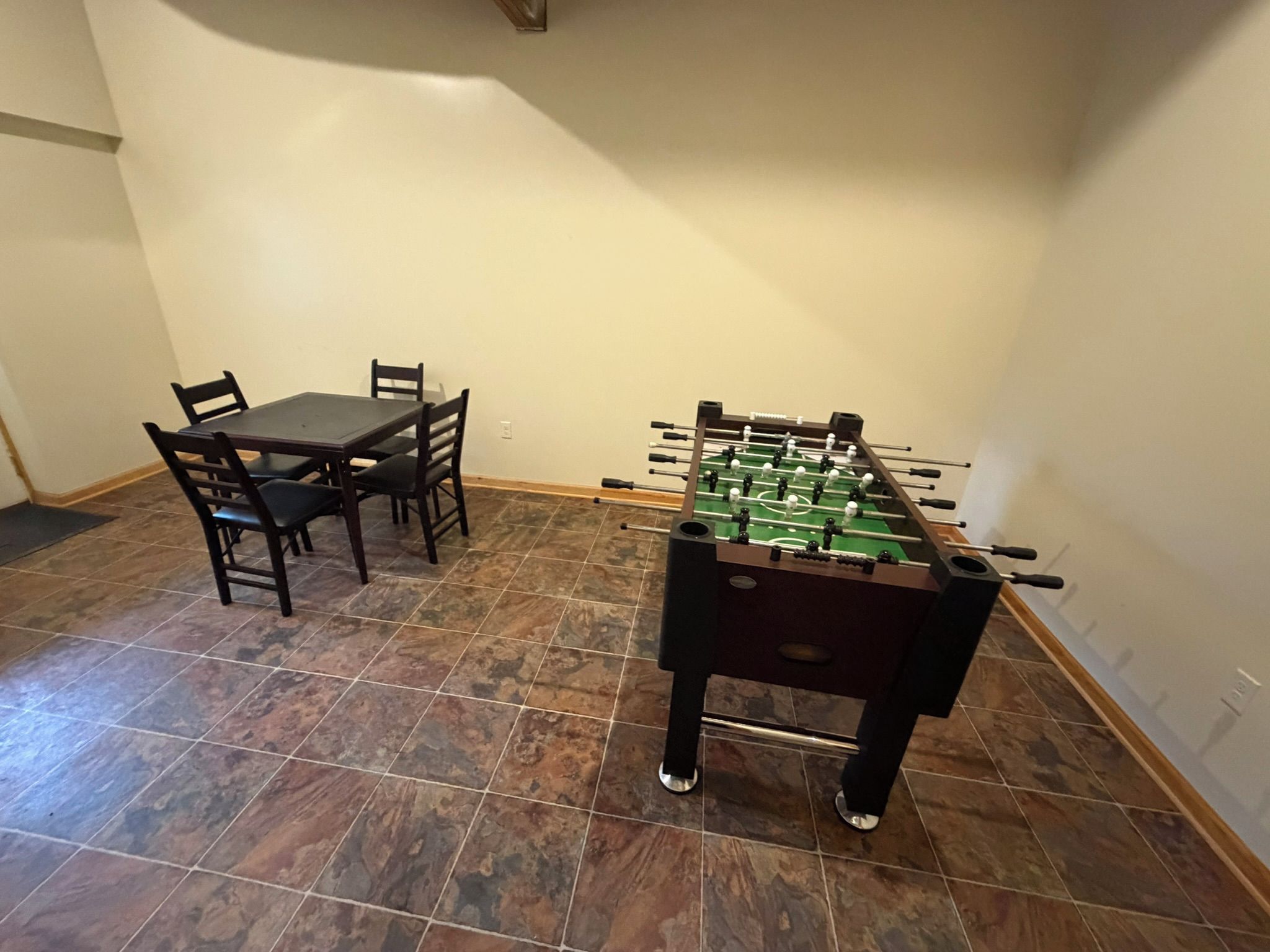 Une pièce avec une table de baby-foot et une table à manger avec des chaises.