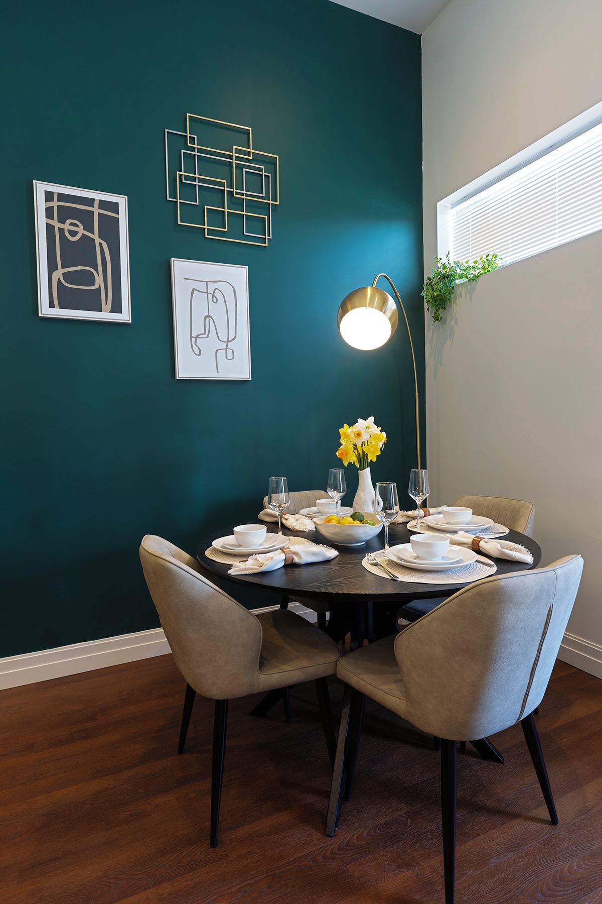 Un coin repas avec une table ronde dressée pour quatre personnes, entourée de chaises.