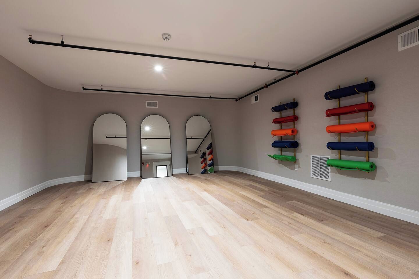 Une pièce spacieuse dotée d’un plancher en bois, d’un système de rails fixé au plafond et d’un mur muni de tubes de rangement codés par couleur.