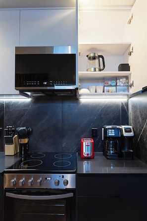 Eine kleine Küche mit Herd, Backofen, Mikrowelle und Kaffeemaschine.