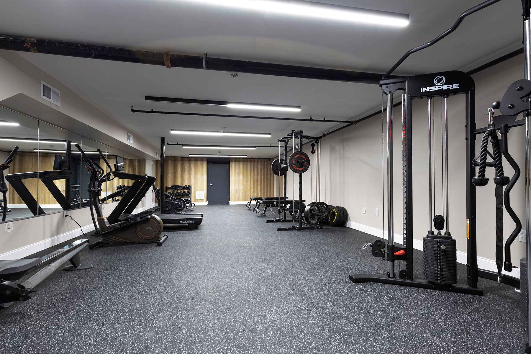 Une salle de sport équipée de tapis de course, d’appareils de musculation et de poids libres.
