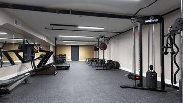 Une salle de sport équipée de tapis de course, d’appareils de musculation et de poids libres.