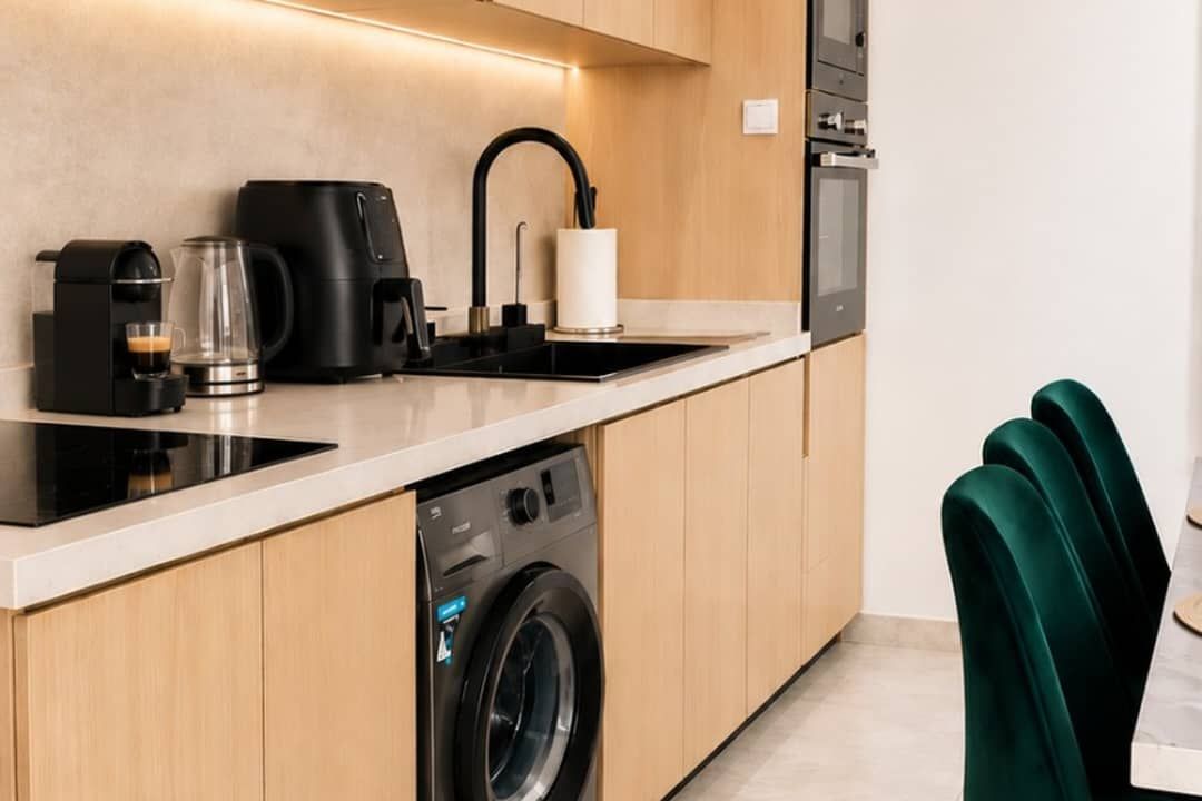 Et moderne køkken med en indbygget vaskemaskine, kaffemaskine og elkedel.