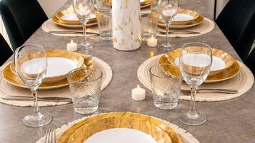 A dining table set with gold-rimmed plates, clear glassware, and a marble centerpiece.
