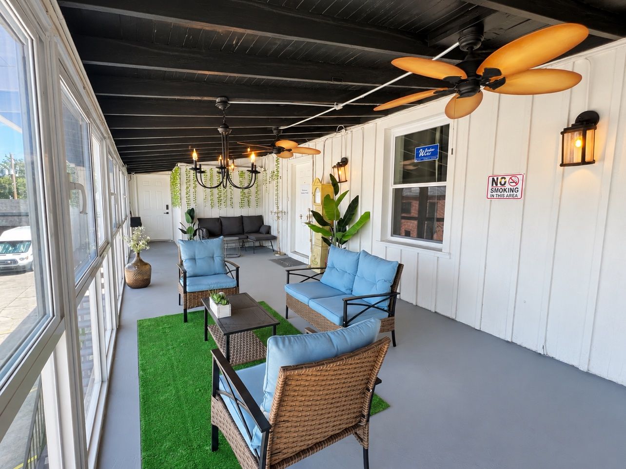A covered outdoor seating area with wicker furniture, a ceiling fan, and a 'No Smoking' sign.