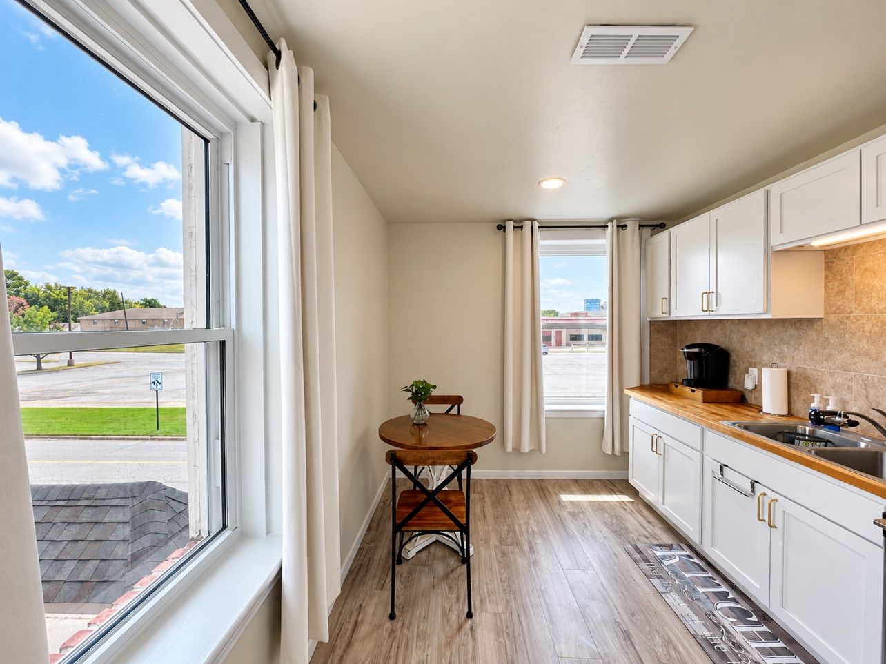 A compact kitchen with a dining area, a window with curtains, and a view of the outside.