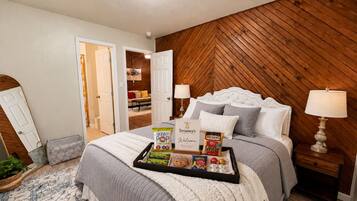 A bedroom with a bed, bedside tables, a tray with snacks, and a door leading to another room.