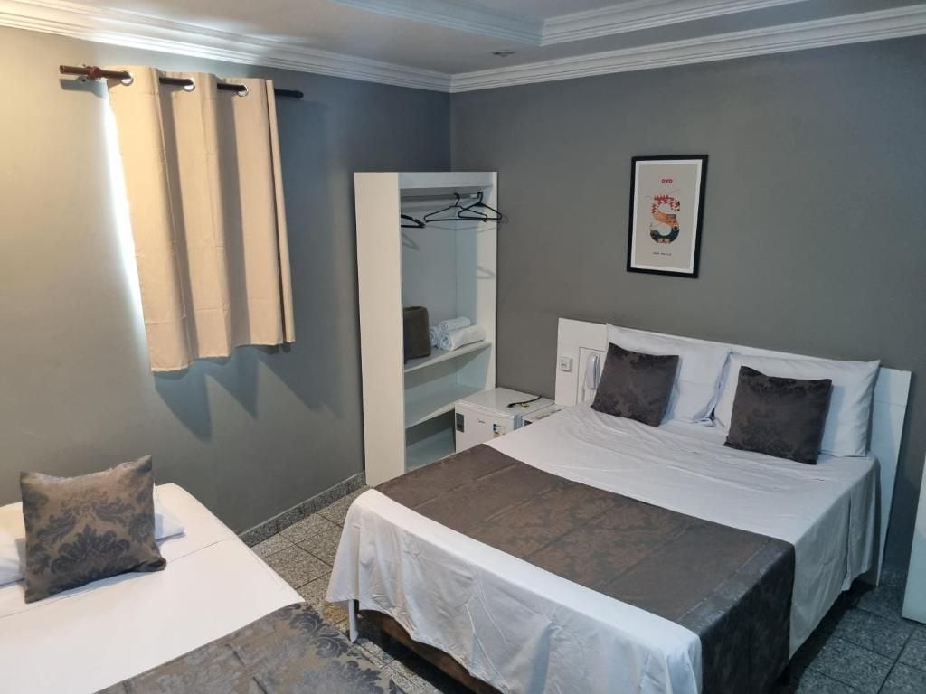 Una habitació d'hotel amb un llit, una taula de nit, un armari i un quadre al mur.