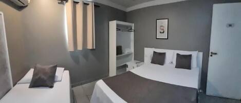 A hotel room with two beds, a wardrobe, a mirror, and a ceiling light.