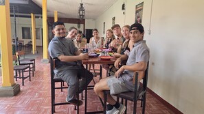 A group of people seated around a table in a room with a tiled floor and wooden chairs. - Casa Mundo Verde - Local Hostel (LEÓN)
