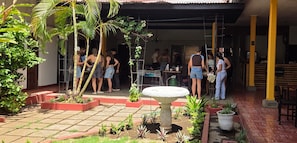 Un patio al aire libre con suelo de piedra, plantas en macetas y una fuente de piedra en el centro.