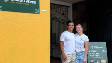 Una coppia in piedi di fronte a un edificio con un cartello che riporta la scritta 'CASA MUNDO VERDE'.
