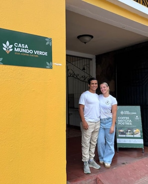 Una pareja de pie frente a un edificio con un letrero que dice 'CASA MUNDO VERDE'.