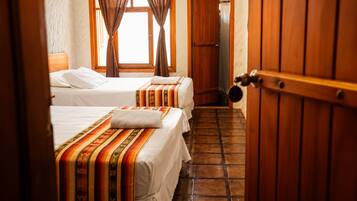 Una habitación de hotel con dos camas, una puerta de madera y piso de baldosas.