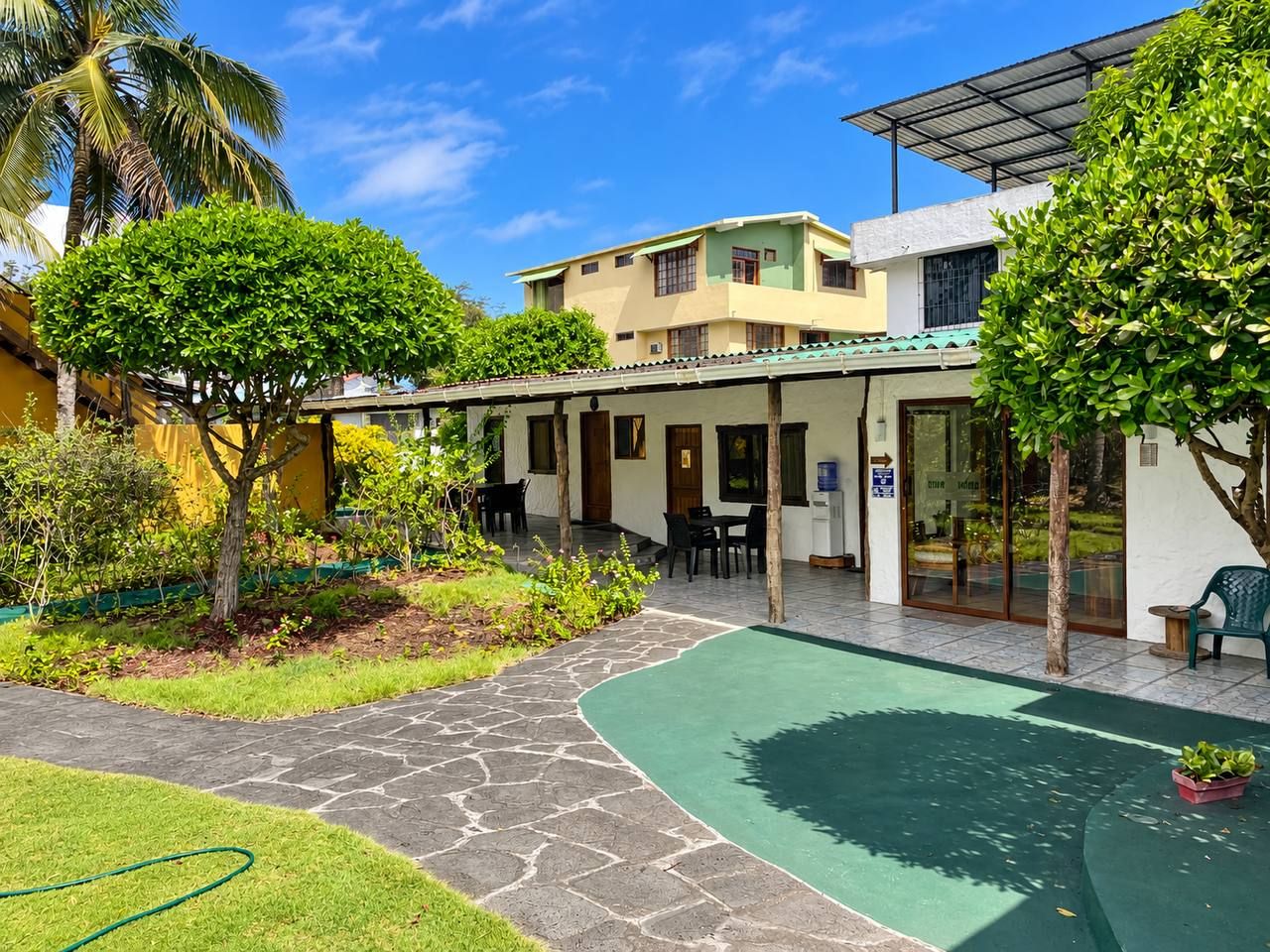 Un patio con piscina, mobiliario exterior y un edificio con techo verde.
