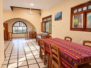 A dining area with a tiled floor, wooden furniture, and a large window with a view.
