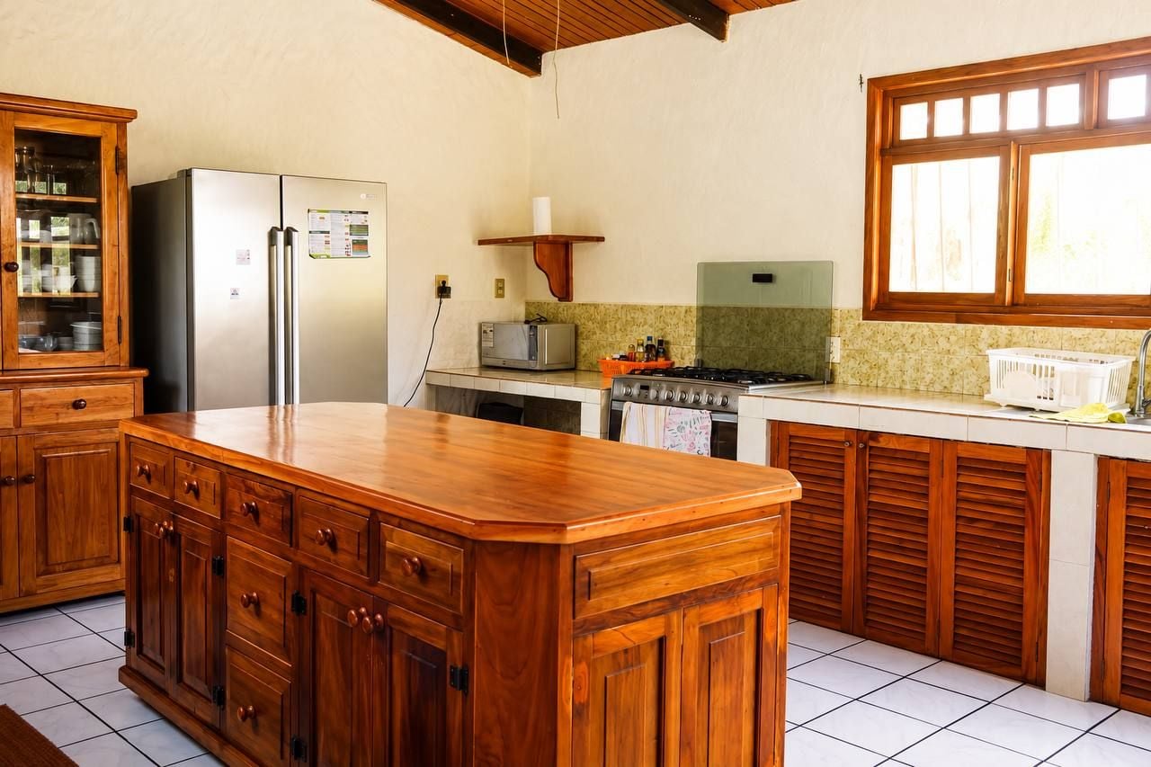 Una cocina con armarios de madera, un refrigerador, un microondas, una estufa y una ventana.