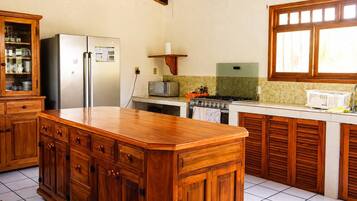 Una cocina con armarios de madera, un refrigerador, un microondas, una estufa y una ventana.
