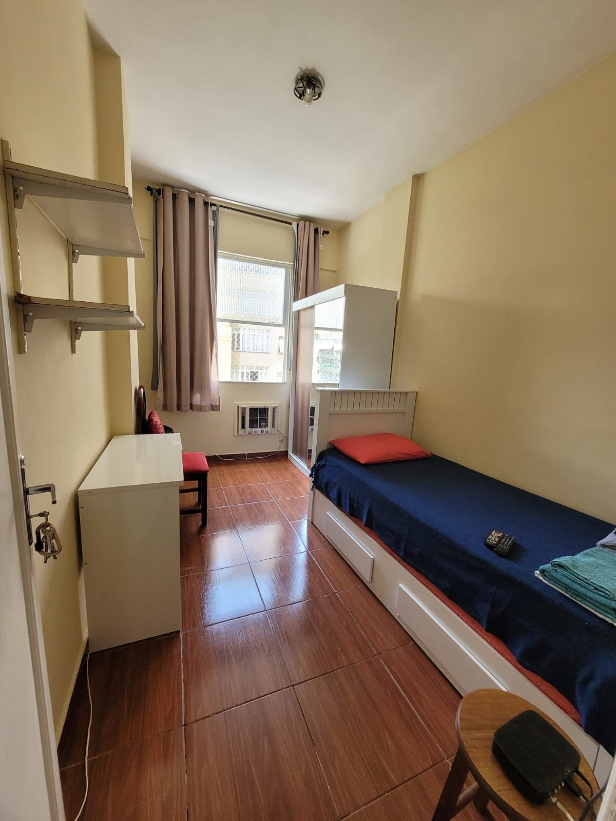 Ein kleines Zimmer mit Bett, Schreibtisch und einer kleinen Küchenzeile.