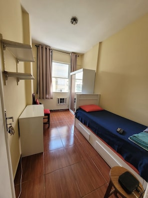 Une pièce de taille modeste comprenant un lit, un bureau et une petite kitchenette.