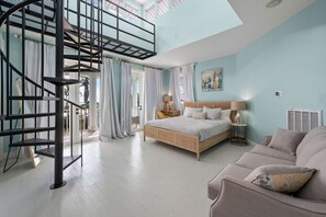 A bedroom with a bed, a sofa, a staircase, and a view of the outdoors. - Skyline Serenity- Heated Pool & Water Views - 3 story Coastal Retreat (Jensen Beach)