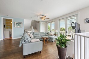 Un salon moderne avec un canapé d’angle, une table basse et une grande plante en pot.