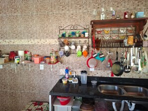 Eine Küche mit einer Fliesenrückwand, einem Topfhalter und verschiedenen Küchenutensilien und Geräten.