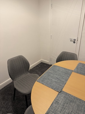 A conference room with a round table, two grey chairs, and a white door. - Beautiful spacious 2 bedroom apartment, 5 minutes from Heaton park. (Manchester)