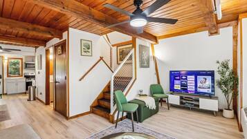 Una sala moderna con techo de madera, una escalera, un televisor de pantalla plana y un comedor.