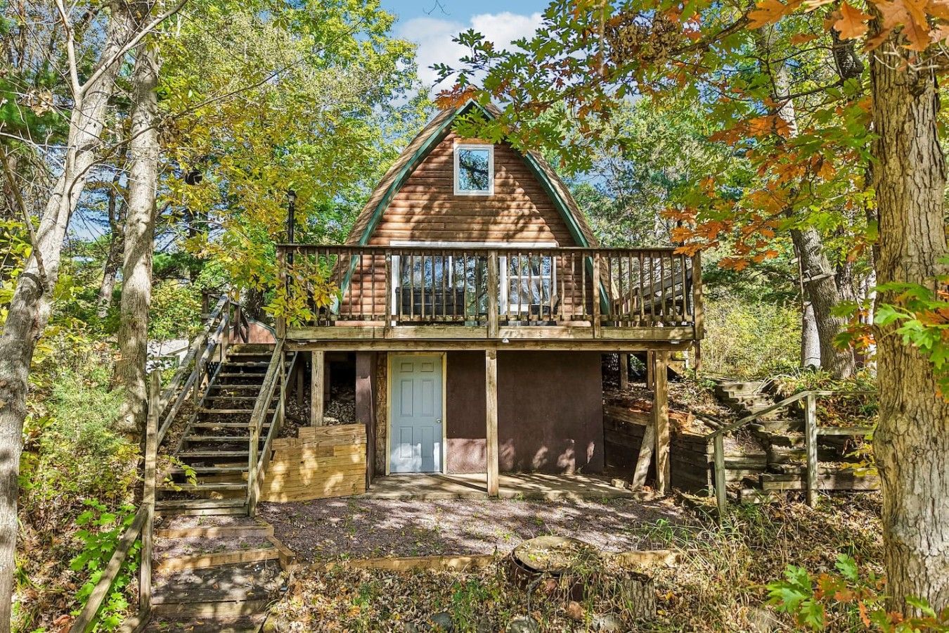 A cabin with a balcony, wooden stairs, and a door.