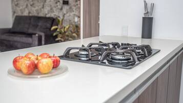 Una cucina con un fornello a gas e un piatto di mele.