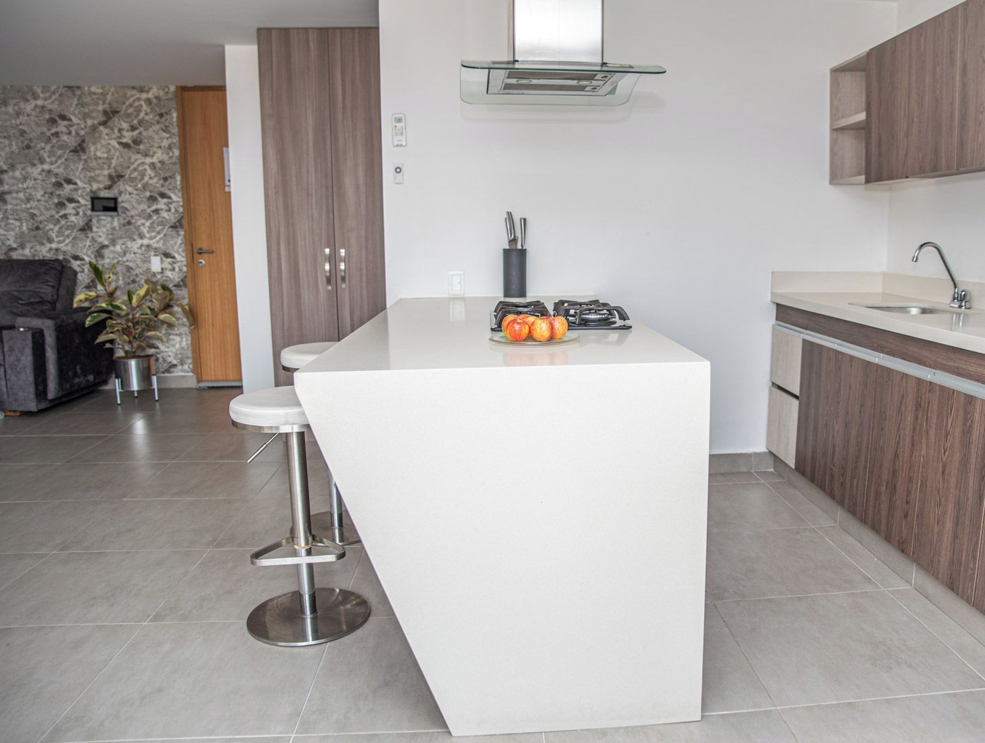 A modern kitchen with a central island, a built-in stove, and a sink.