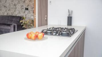 Una cucina moderna con un piano di lavoro bianco, un fornello a gas e un piatto di mele.