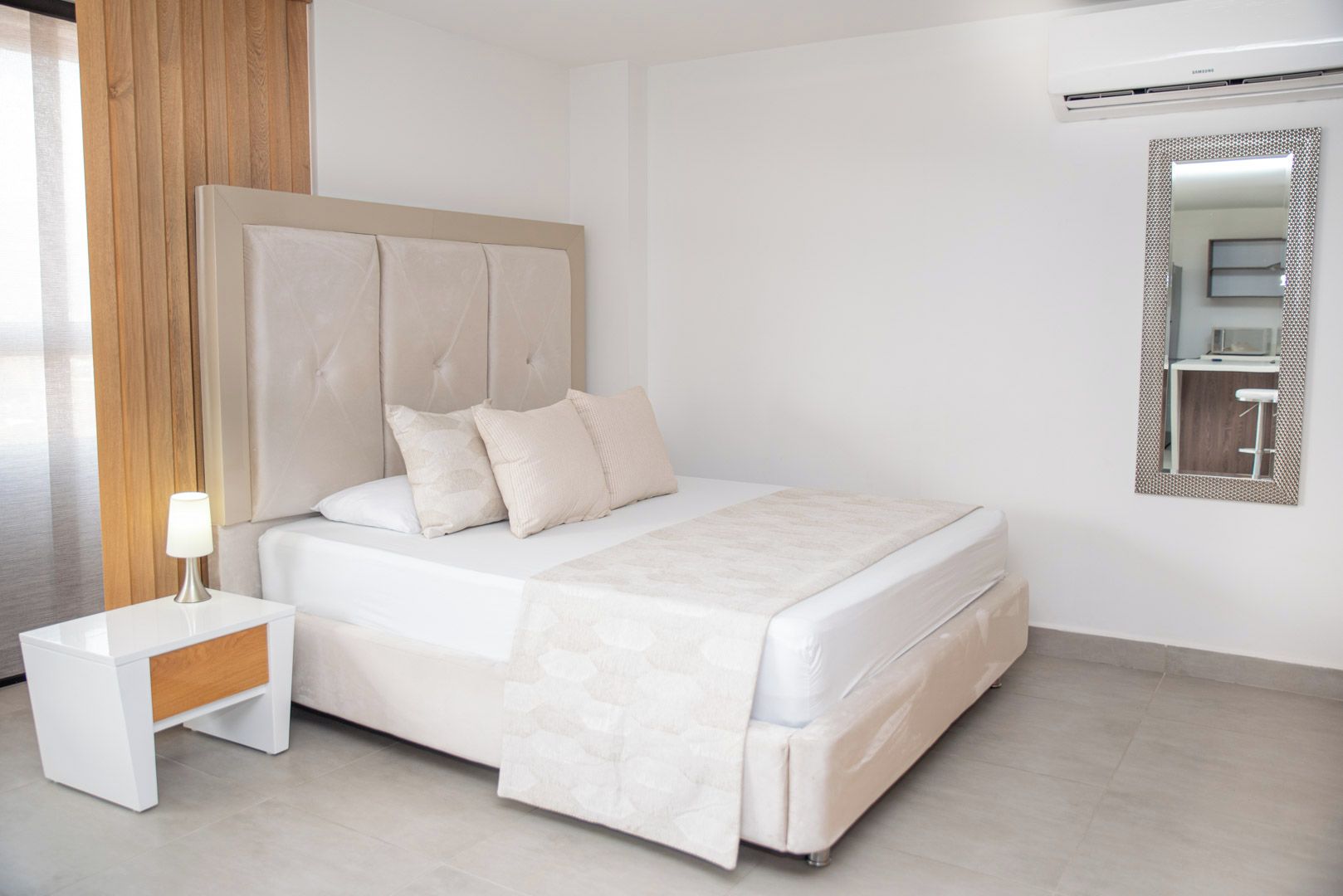 Ein modernes Schlafzimmer mit Bett, Nachttisch, Lampe und Spiegel an der Wand.