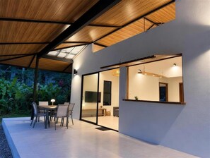Ein modernes Interieur mit Essbereich, einem großen Spiegel und Blick auf einen Garten.