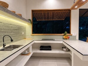 A modern kitchen with a built-in sink, a window with a view of trees, and a wooden ceiling. - New Listing (Cocles)