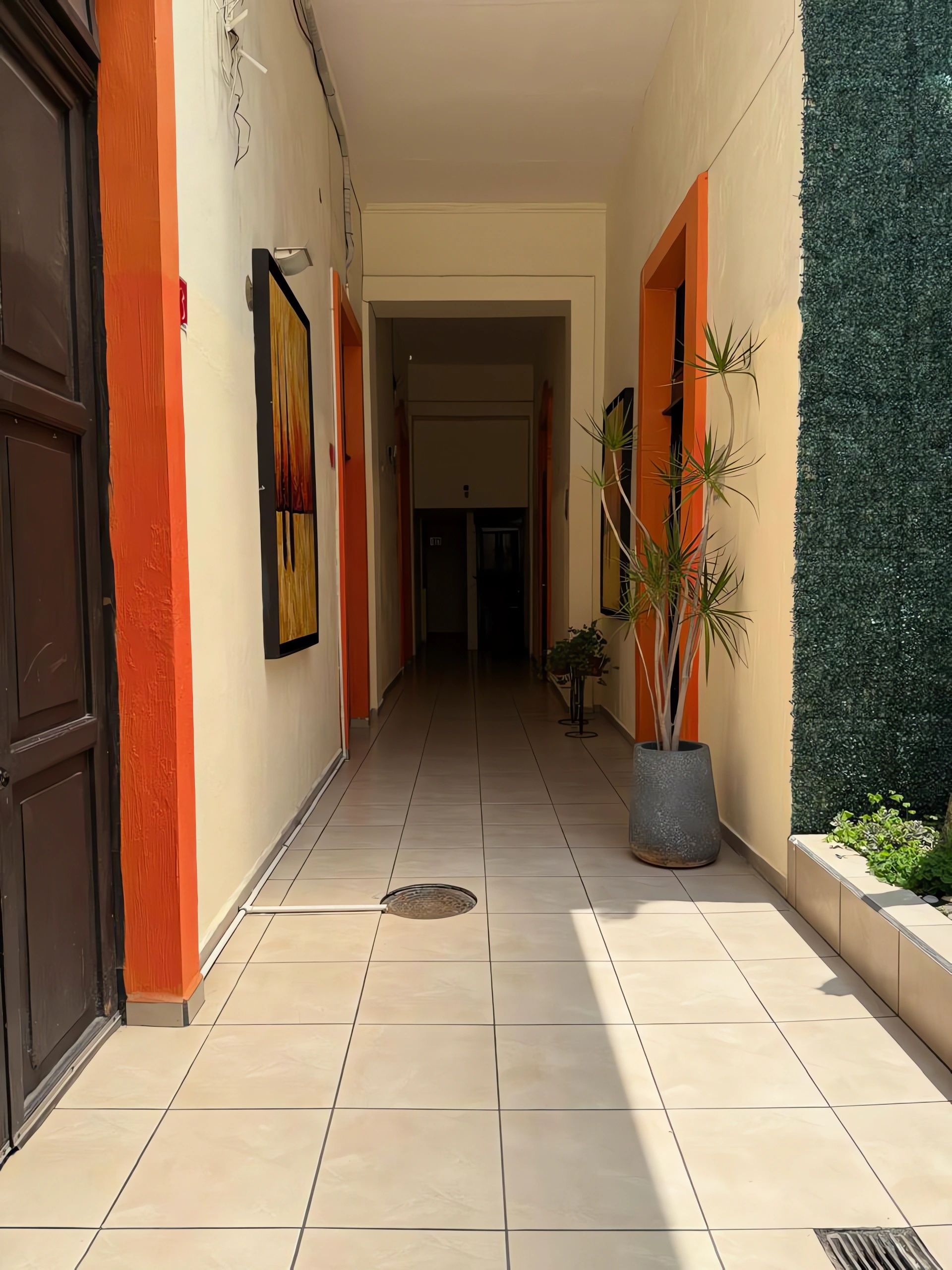 A corridor with tiled flooring, a manhole cover, and a potted plant.