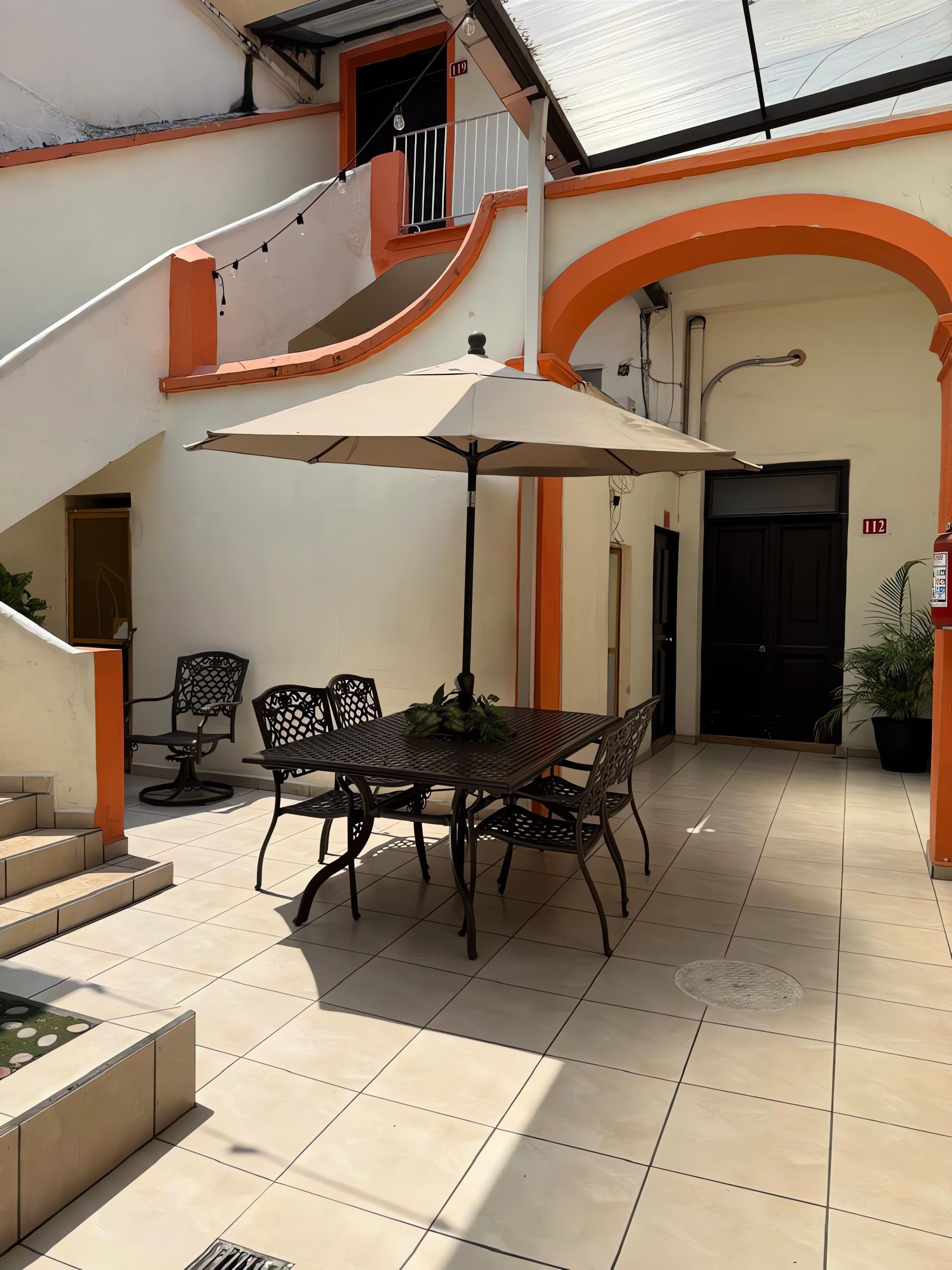 A courtyard with a dining table, chairs, and an umbrella.