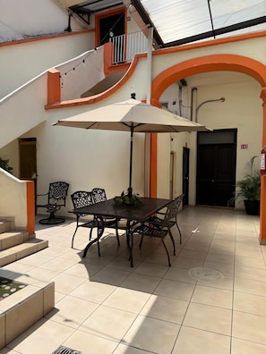 Un patio con una mesa, sillas y una sombrilla.