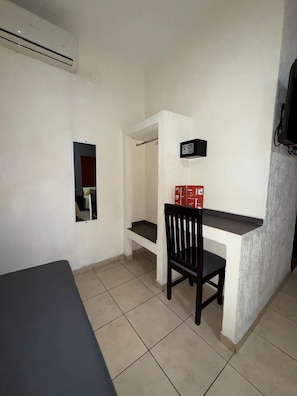 Una habitación con escritorio, silla y aire acondicionado.