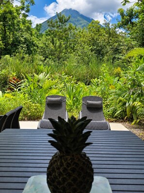 A table with two chairs facing a mountain, surrounded by lush greenery. - Casa Viridia  Hot pool Arenal Volcano view (La Fortuna)