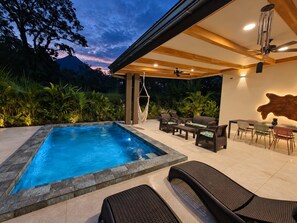 A pool area with a hot tub, lounge chairs, and a table with chairs. - Casa Viridia  Hot pool Arenal Volcano view (La Fortuna)