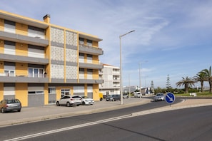 A multi-story residential building with balconies, a parking area, and a clear sky. - Balance House Surf in Peniche (Peniche)
